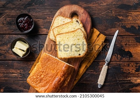 Brioche bread on breakfast table with butter and jam. Wooden background. Top view