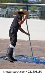 BRISBANE, AUS - SEP 25 2014:A Local Swimming Pool Service Technician Using A Pool Skimmer To Remove Debris From A Courtyard Fountain In Brisbane Waterfront, Australia. 