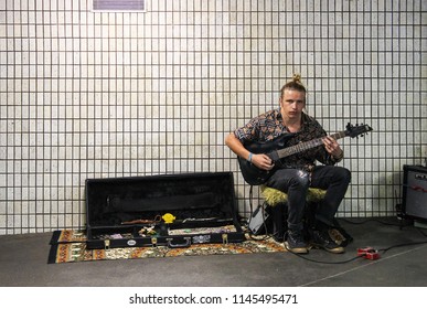 Brisbane Australia 8 5 2015  Young Man With Man Bun And Torn Jeans Plays Electric Guitar For Tips In Subway Set Up By Dirty Tile Wall.