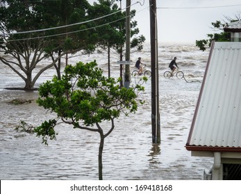 BRISBANE, QLD, AUSTRALIA - January 27: A pair of cyclists ride along the sea wall during the storm surge floods in Sandgate on 27 January 2013