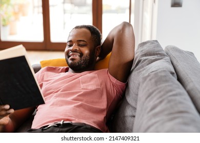 Bristle Black Man Reading Book While Resting On Sofa At Home