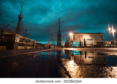 Bristol, UK - August 04 2021: Long Exposure Of Neon Lit City Docks Reflected In Puddle At Night