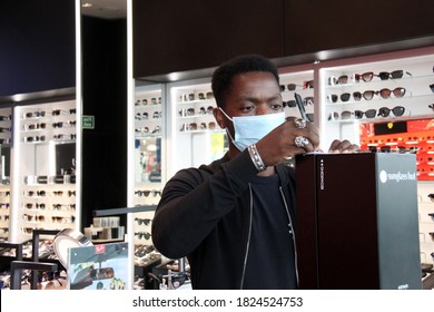 Bristol, UK September 29, 2020: Young Black Male Retail Assistant At Work In Sunglasses Shop Wearing Face Covering