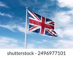 Britain flag waving at cloudy sky background. United Kingdom (UK) flag.