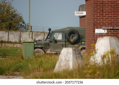 a British Army Land Rover Defender infantry vehicle parked in a secure military compound