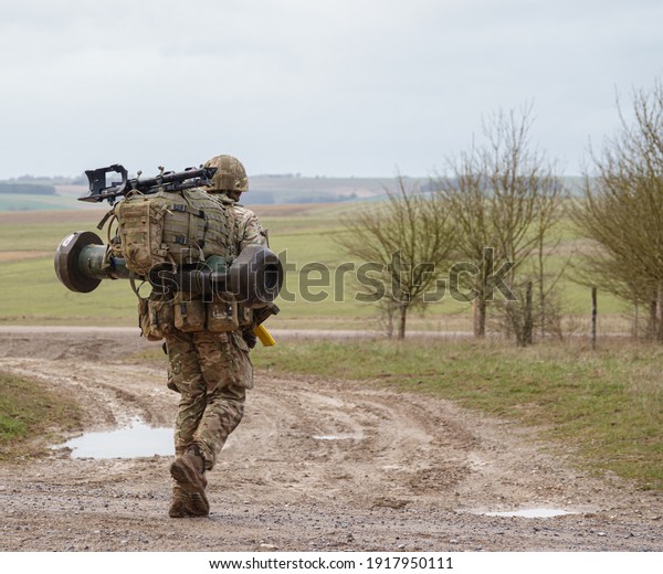 British army soldier completing\
an 8 mile combat fitness test tabbing exercise with fully loaded\
25Kg bergen and NLAW (MBT-LAW, RB-57) anti-tank guided\
missile