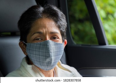 British Asian woman (BAME) wearing face mask in a car. COVID or Coronavirus concept, prevention and self-isolating in UK.