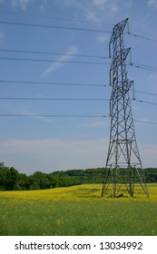 British Electricity Pylon Carrying UK National Grid High Voltage Power Cables In A Farmers Rapeseed Crop Field