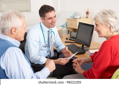 British GP Talking To Senior Couple In Surgery