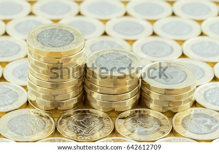 British money, new pound coins in three stacks on a background of more money. New one pound coins introduced in 2017