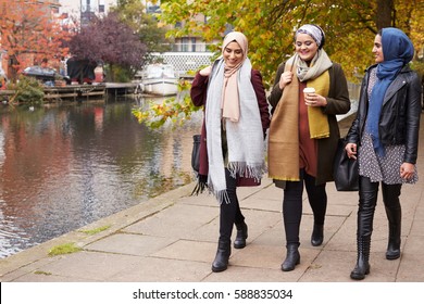 British Muslim Female Friends Walking By River In City