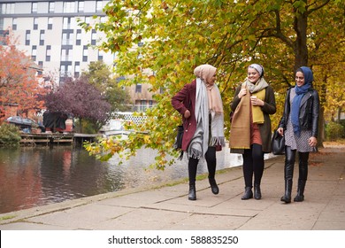 British Muslim Female Friends Walking By River In City