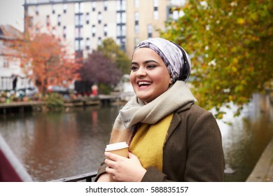 British Muslim Female With Takeaway Coffee By River In City - Powered by Shutterstock