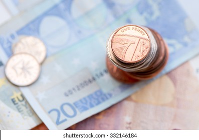 British one penny coin on a pile of coins and 20 Euro note
