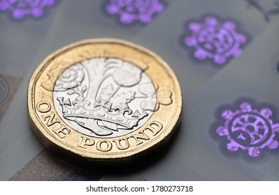 British One Pound coin. Placed on top of blurred new polymer 20 pound note surface with holograms. 