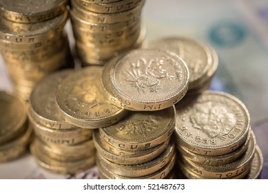 British Pound Coins against a background of British assorted bank notes

