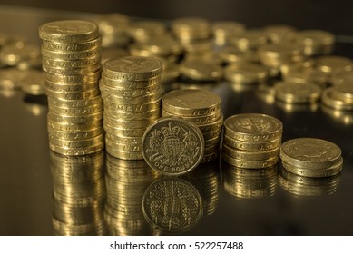 British pound coins neat stacks up close macro studio shot against a shiny reflective black background