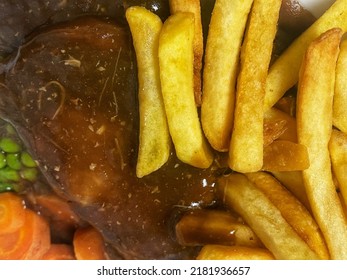 British Pub Food Meal Of Steak Pie Served With Chips And Gravy On A Plate 