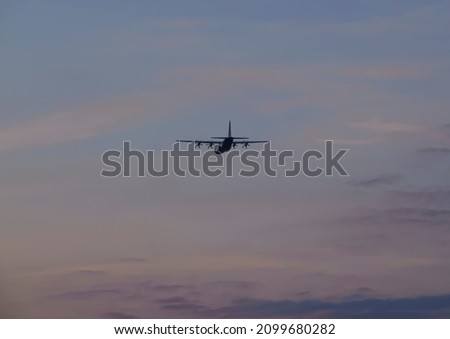 British RAF Hercules C-130J aerial air-to-air refuelling aircraft flying into a warm red purple sunset sky Wiltshire, UK