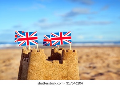 British Seaside Traditional Sand Castle On The Beach With Union Jack Flags