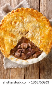 British Steak And Ale Pie Is A Tender Pieces Of Steak Are Cooked With Vegetables And English Ale, Then Wrapped In A Flaky Buttery Crust Closeup In The Dish On The Table. Vertical Top View From Above
