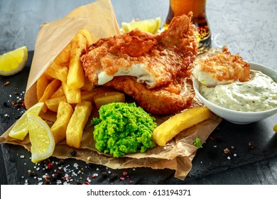 British Traditional Fish and chips with mashed peas, tartar sauce on crumpled paper with cold beer. - Powered by Shutterstock