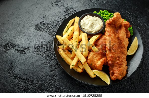 British Traditional Fish and chips with mashed\
peas, tartar sauce and cold\
beer.