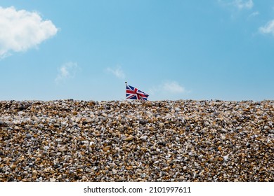 British Union Jack Flag Flying Above A Pebble Beach