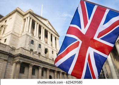 British Union Jack flag flying in front of the traditional architecture of the Bank of England in the financial center of the old city of London, UK