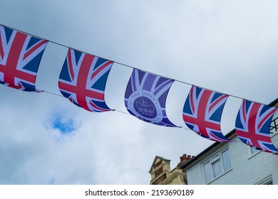 British Union Jack Flags commemorating the Queen's 70th anniversary celebrations flying across a town centre street against a cloudy sky - Powered by Shutterstock