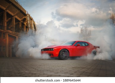 Brno, Czech Republic - April 12 2015: Red Dodge Challenger SRT Hellcat shrouded in smoke from its burning tires.