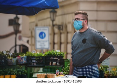 Brno, Czech Republic - April 24 2020: A Vendor At A Farmer's Market Stall Wearing A Cloth Face Mask. He Protecting Himself From Corona Virus And Other Airborne Particles And Diseases.