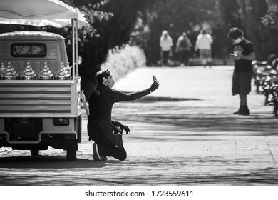 Brno, Czech Republic - April 25 2020: An Ice Cream Vendor With A Cloth Face Mask Taking A Selfie Photo In Front Of His Ice Cream Truck Standing In A Public Park.