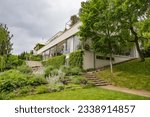 BRNO, CZECH REPUBLIC (CZECHIA) – JUNE 6, 2023: Exterior of the functionalist Villa Tugendhat (Vila Tugendhat) from side and its garden on a cloudy day, South Moravian Region (Jihomoravský kraj)