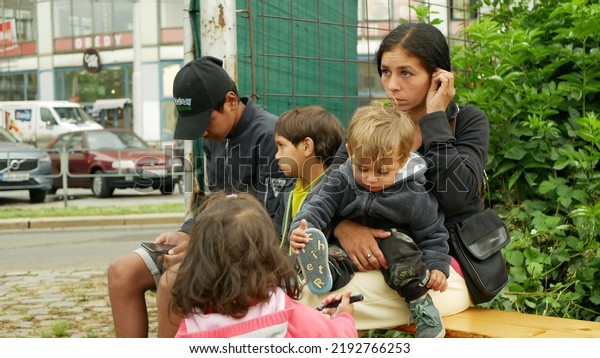 BRNO,\
CZECH REPUBLIC, JUNE 10, 2022: Refugees Ukraine Gypsy detention\
camp Gypsies immigrants people family Roma children mother Gipsy\
placement in Brno train station sitting on\
bench