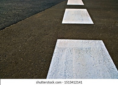 Broad Dashed White Line In Perspective Painted With Reflective Paint On Black Asphalt Tarmac Road.