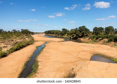 Broad dry river with small trickle of water and animal tracks crossing to pools in Kruger National park in South Africa