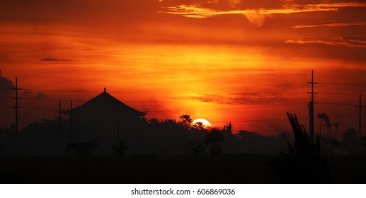 Broad view of a number of posts with various cables, a typical balinese asian house roof and a picturesque evening sky on Bali, Indonesia, for travel and touristic concepts