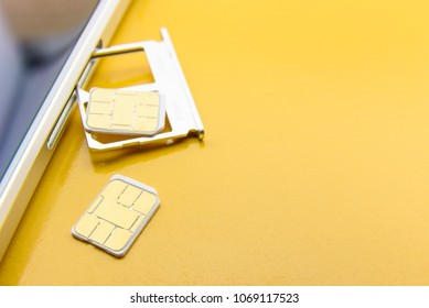 Broadband 5G Mobile Communication Technology Concept : SIM Card Tray / Dual SIM Card Slot With Two Nano SIM Cards On Yellow Background. SIM Stores International Mobile Subscriber Identity IMSI Number.