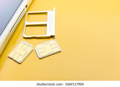 Broadband 5G Mobile Communication Technology Concept : SIM Card Tray / Dual SIM Card Slot With Two Nano SIM Cards On Yellow Background. SIM Stores International Mobile Subscriber Identity IMSI Number.