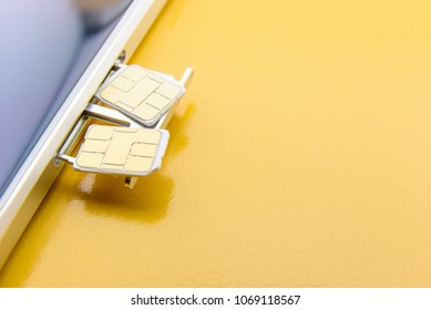 Broadband 5G Mobile Communication Technology Concept : SIM Card Tray / Dual SIM Card Slot With Two Nano SIM Cards On Yellow Background. SIM Stores International Mobile Subscriber Identity IMSI Number.