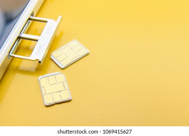 Broadband 5G Mobile Communication Technology Concept : SIM Card Tray / Dual SIM Card Slot With Two Nano SIM Cards On Yellow Background. SIM Stores International Mobile Subscriber Identity IMSI Number.