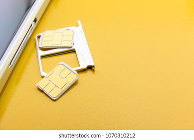 Broadband 5G Mobile Communication Technology Concept : SIM Card Tray / Dual SIM Card Slot With Two Nano SIM Cards On Yellow Background. SIM Stores International Mobile Subscriber Identity IMSI Number.