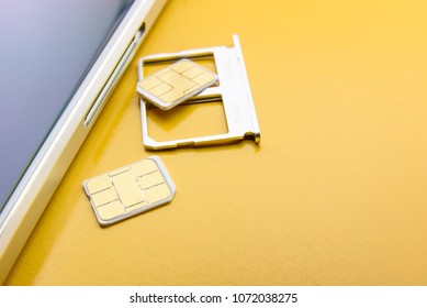 Broadband 5G Mobile Communication Technology Concept : SIM Card Tray / Dual SIM Card Slot With Two Nano SIM Cards On Yellow Background. SIM Stores International Mobile Subscriber Identity IMSI Number.