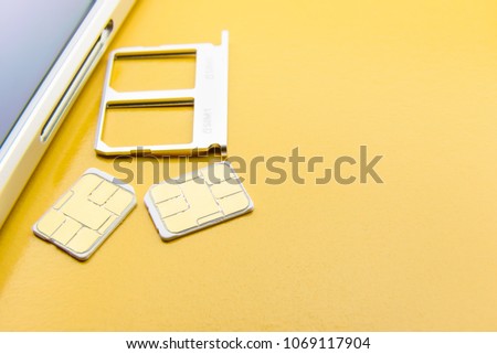 Broadband 5G mobile communication technology concept : SIM card tray / dual SIM card slot with two nano SIM cards on yellow background. SIM stores international mobile subscriber identity IMSI number.