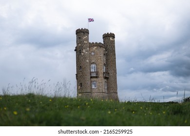 Broadway Tower English British Castle Architecture With Union Jack Flying On A Moody Day With Dark Characterful Clouds. Shot In June 2022 HD Background Monarchy Shot.