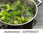 Broccoli is blanched in boiling water in a stainless steel pot to preserve the fresh green color, healthy cooking with vegetables, copy space, selected focus, narrow depth of field