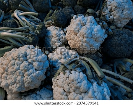 Broccoli and cauliflower vegetables are sold in the market stacked randomly