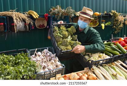 Broccoli At The Farmers' Market.
A Male Salesperson Puts A Box Of Broccoli On The Counter. The Seller In A Protective Medical Mask.