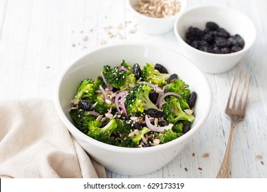 Broccoli With Raisins, Red Onions And Seeds. Healthy Raw Diet Salad. In A White Bowl On A Blue Wooden Background